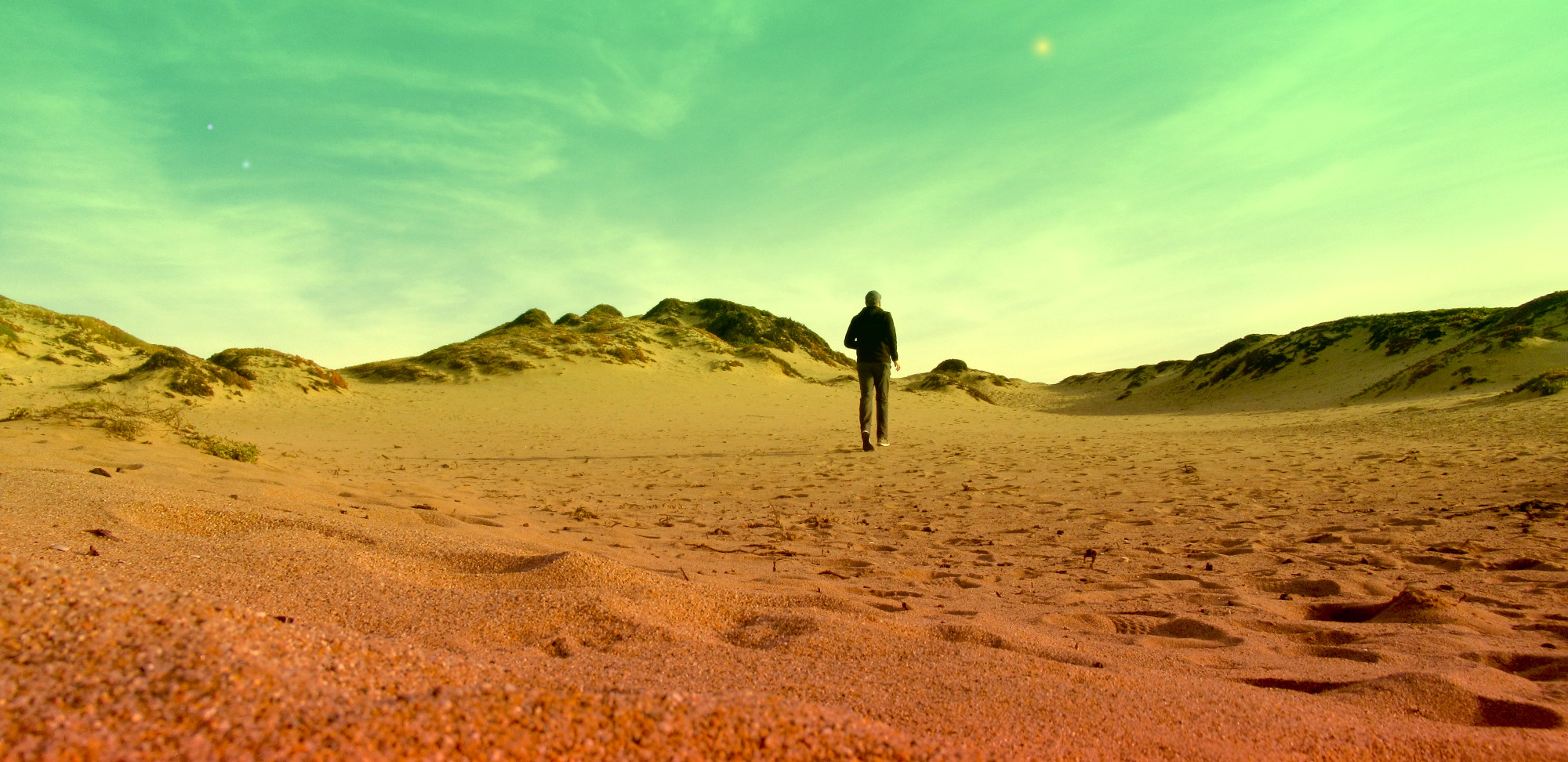 A grown man hustling across some sand before his camera timer goes off